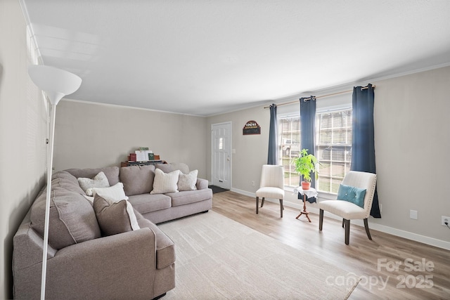 living area with baseboards, light wood-type flooring, and crown molding