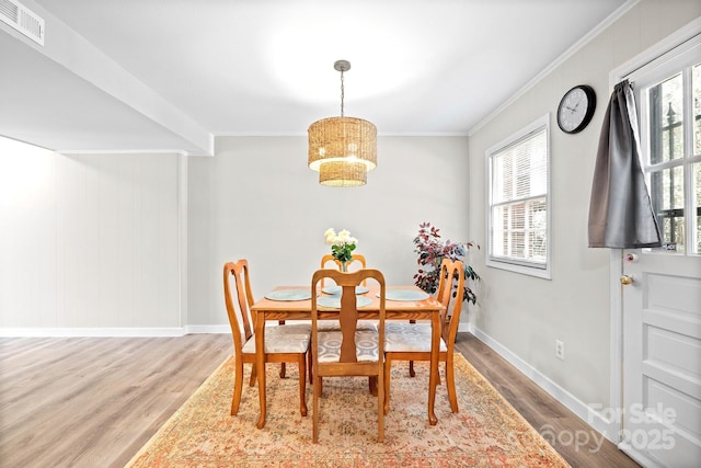 dining room with ornamental molding, light wood-type flooring, visible vents, and plenty of natural light