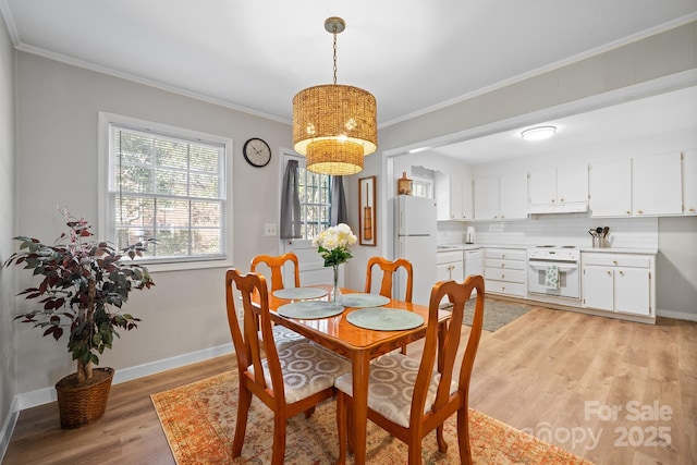 dining space with light wood-style floors, baseboards, and ornamental molding