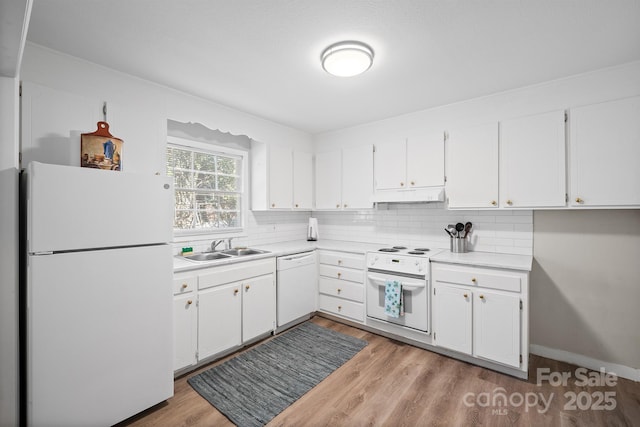 kitchen featuring tasteful backsplash, white appliances, a sink, and under cabinet range hood