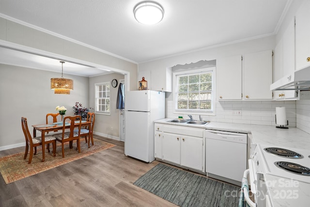 kitchen with white appliances, a sink, light countertops, light wood-type flooring, and plenty of natural light