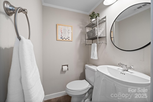 half bathroom featuring toilet, wood finished floors, visible vents, baseboards, and crown molding