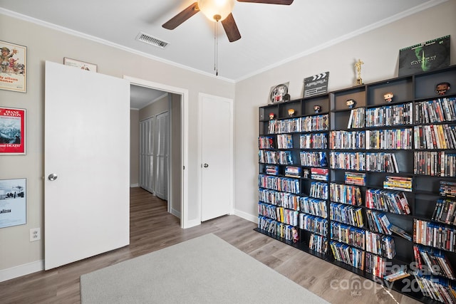 sitting room featuring wood finished floors, a ceiling fan, baseboards, visible vents, and crown molding