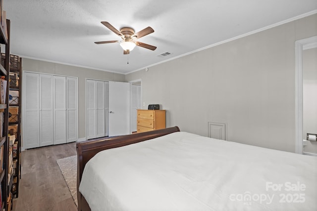 bedroom with ornamental molding, visible vents, and wood finished floors