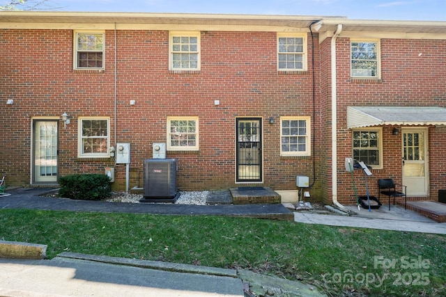 rear view of house with a yard, brick siding, and cooling unit