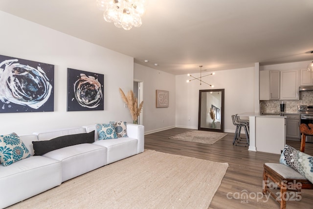 living room with sink, a notable chandelier, and dark hardwood / wood-style flooring