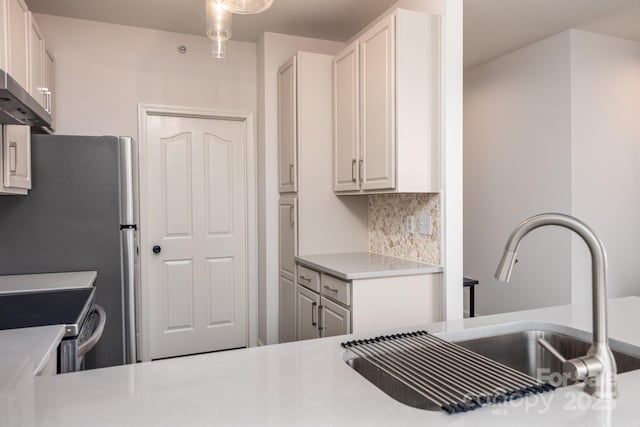 kitchen featuring pendant lighting, sink, white cabinets, backsplash, and wall chimney exhaust hood