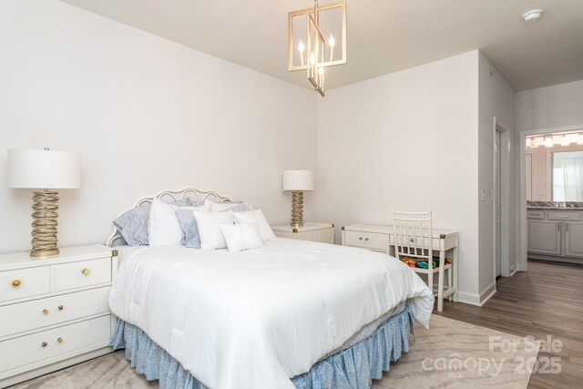 bedroom featuring connected bathroom, a notable chandelier, and light wood-type flooring