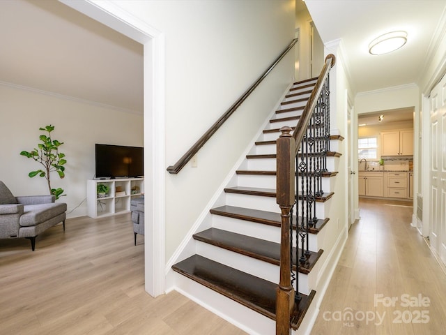 staircase with crown molding and wood finished floors