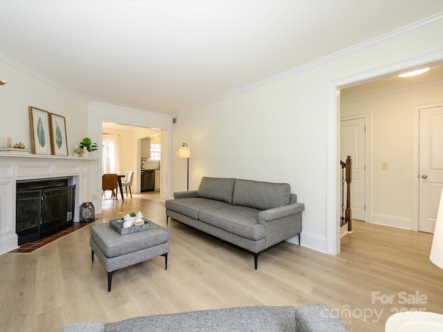 living room with light wood-type flooring, a fireplace with flush hearth, ornamental molding, and baseboards