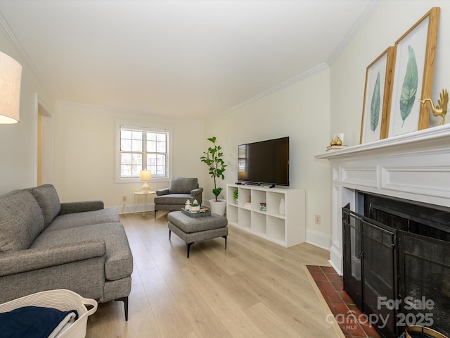 living area featuring a fireplace with flush hearth, crown molding, baseboards, and wood finished floors