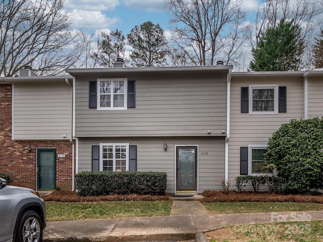 townhome / multi-family property with brick siding and a chimney