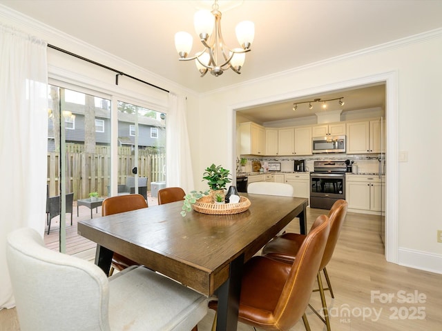 dining room featuring light wood finished floors, ornamental molding, baseboards, and a notable chandelier