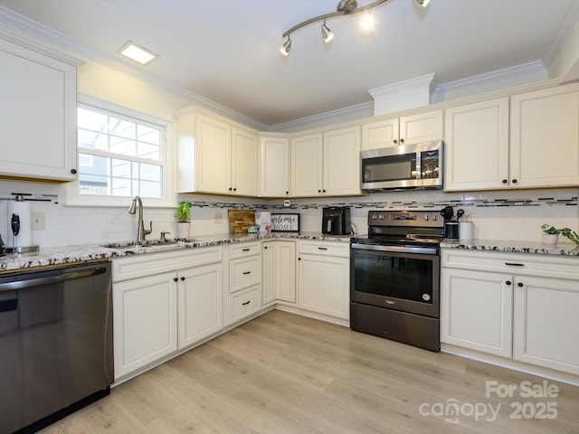 kitchen with light stone counters, ornamental molding, stainless steel appliances, light wood-type flooring, and a sink