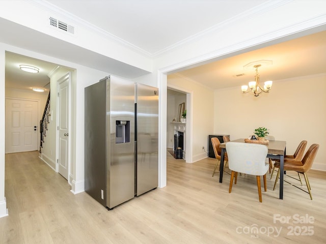 kitchen with ornamental molding, light wood-type flooring, stainless steel fridge, and a notable chandelier