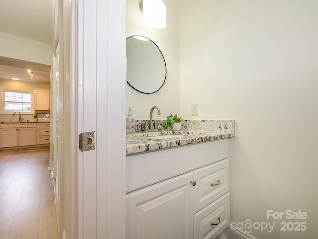 bathroom with crown molding, vanity, and wood finished floors