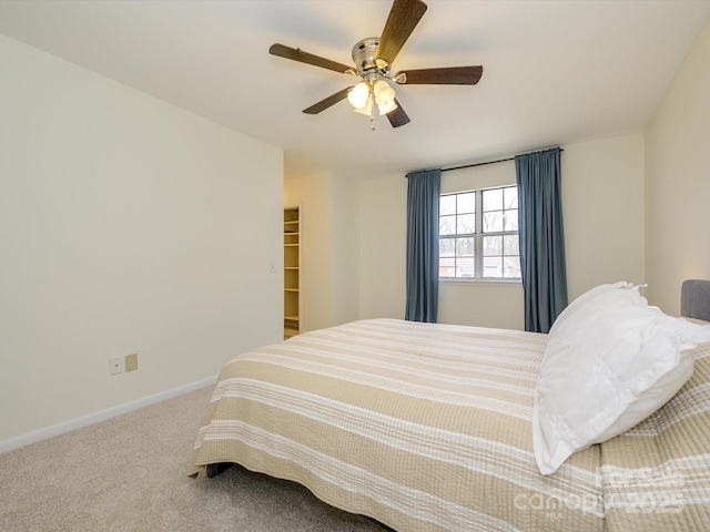 bedroom featuring a ceiling fan, baseboards, a walk in closet, and carpet flooring