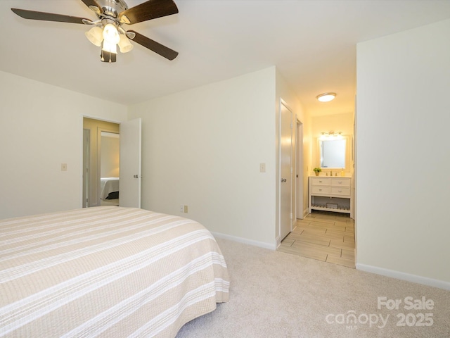 bedroom featuring light carpet, ceiling fan, baseboards, and ensuite bathroom