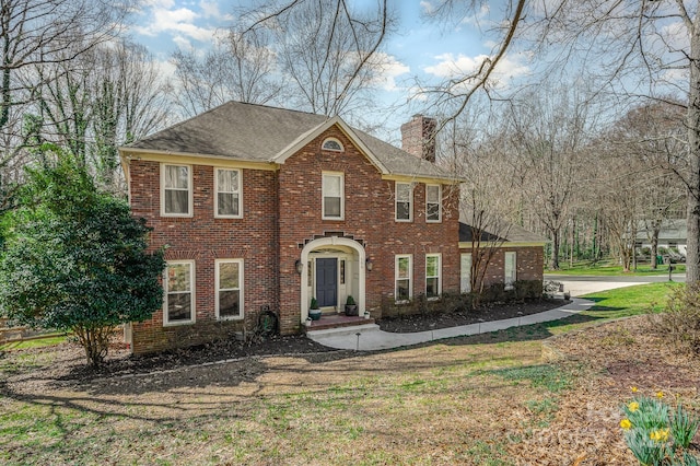 view of front of house featuring brick siding, a chimney, a shingled roof, and a front yard