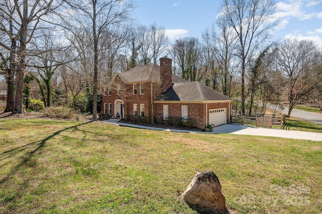 georgian-style home featuring a garage, brick siding, a chimney, and a front lawn