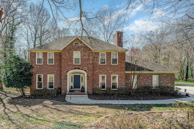 view of front facade with brick siding and a chimney