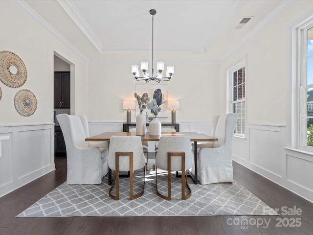 dining room featuring a raised ceiling, wood finished floors, visible vents, and a healthy amount of sunlight