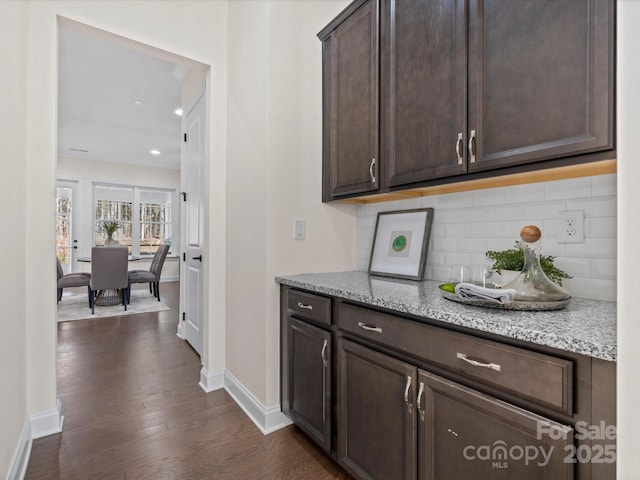 bar with dark wood-style floors, backsplash, and baseboards