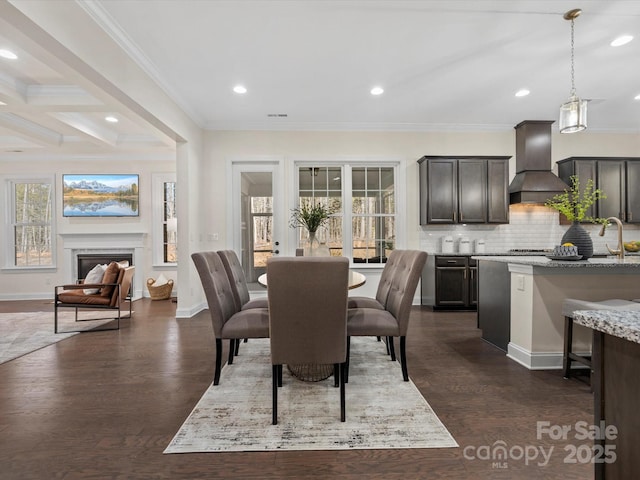 dining room featuring dark wood-style flooring, a fireplace, recessed lighting, ornamental molding, and baseboards