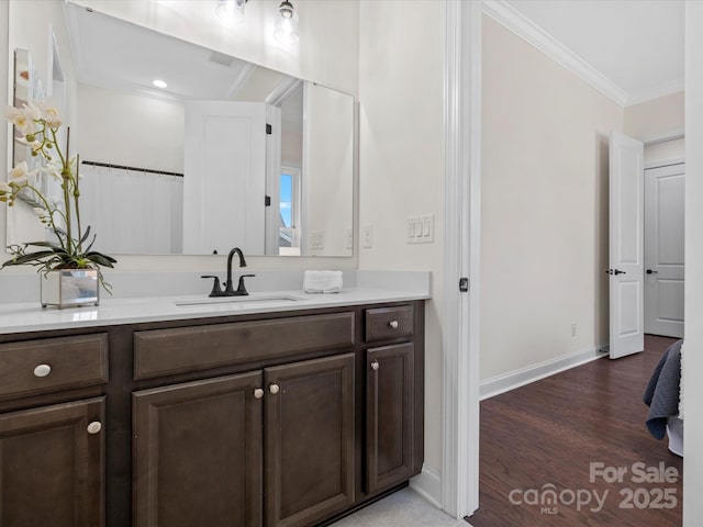 bathroom featuring baseboards, wood finished floors, vanity, and crown molding