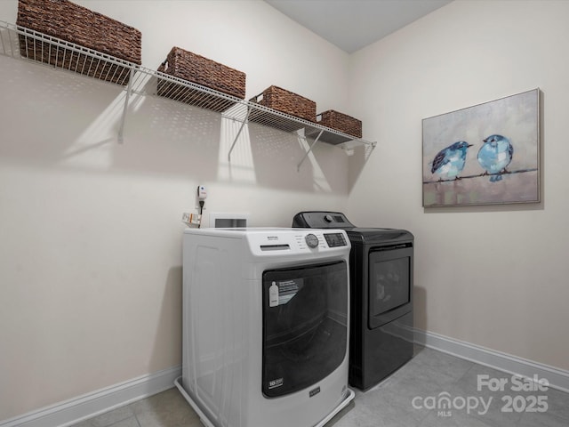 laundry room featuring washing machine and dryer, laundry area, tile patterned flooring, and baseboards