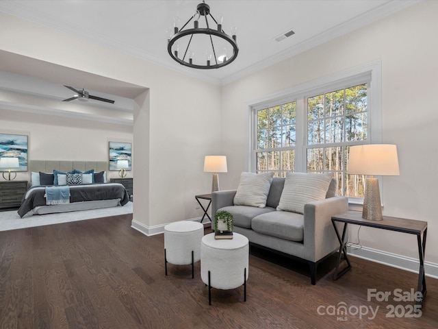 living room with visible vents, ornamental molding, wood finished floors, baseboards, and ceiling fan with notable chandelier