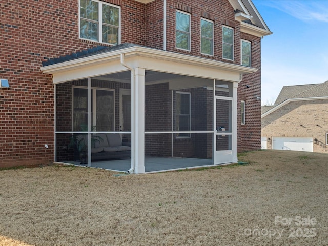 view of side of home with a yard, brick siding, and a sunroom