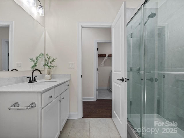 bathroom featuring a stall shower, a walk in closet, vanity, and tile patterned floors