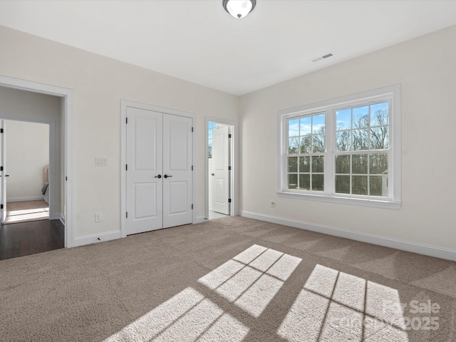 unfurnished bedroom featuring carpet, visible vents, and baseboards