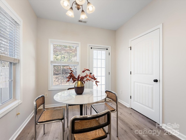 dining space with an inviting chandelier and light hardwood / wood-style flooring