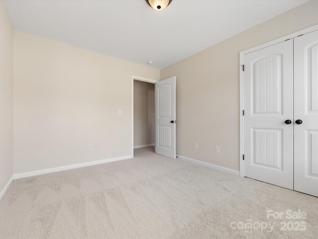 unfurnished bedroom featuring light carpet and a closet