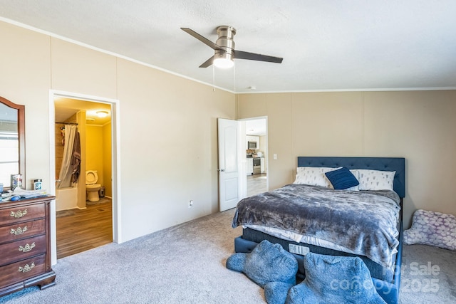 carpeted bedroom with ornamental molding, ensuite bathroom, and ceiling fan