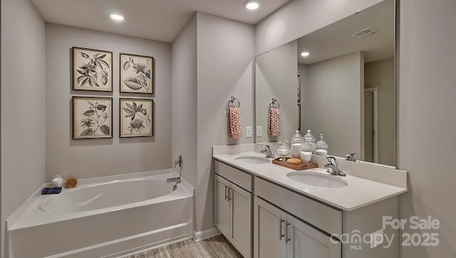 bathroom featuring vanity, wood-type flooring, and a tub