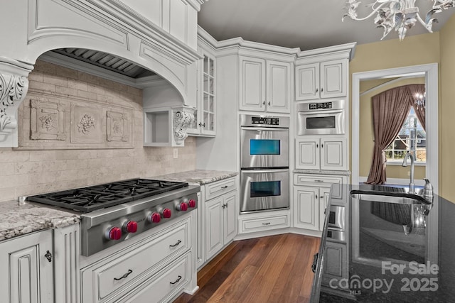 kitchen with dark wood-style flooring, an inviting chandelier, glass insert cabinets, appliances with stainless steel finishes, and white cabinets