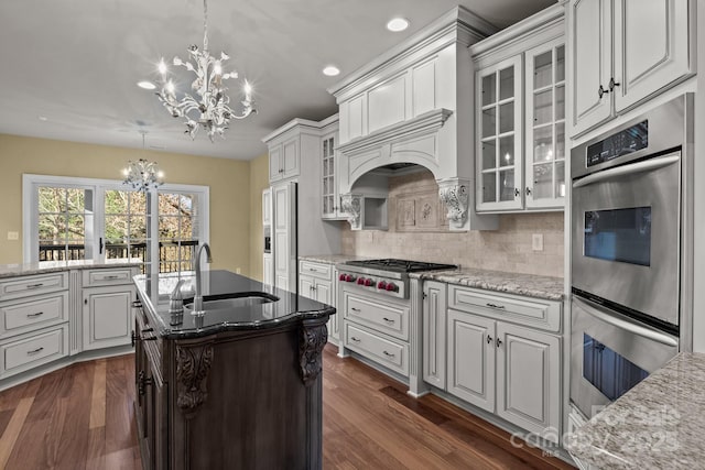 kitchen with glass insert cabinets, decorative light fixtures, an inviting chandelier, stainless steel appliances, and a sink