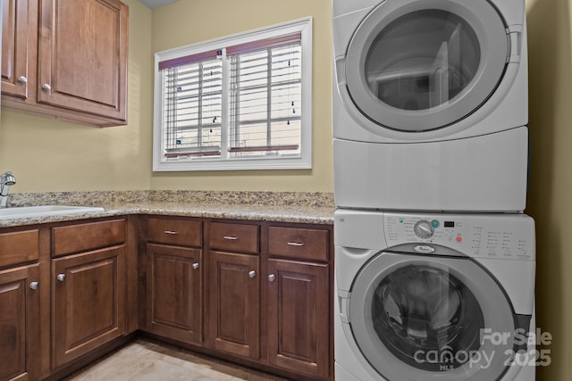 washroom featuring stacked washer / dryer, cabinet space, and a sink