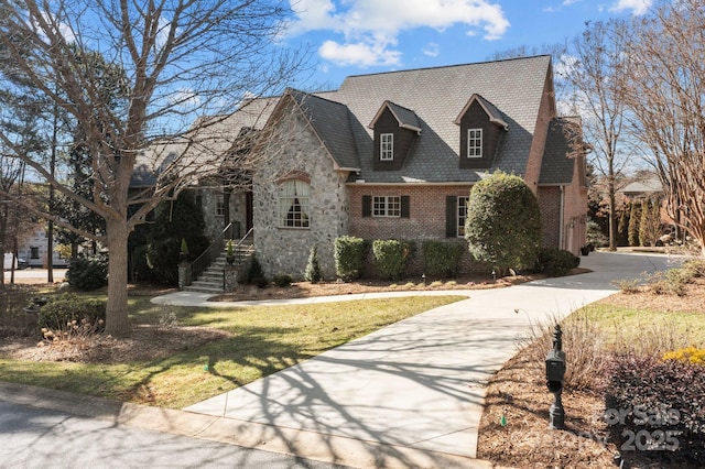 view of front of property featuring stone siding, concrete driveway, and brick siding