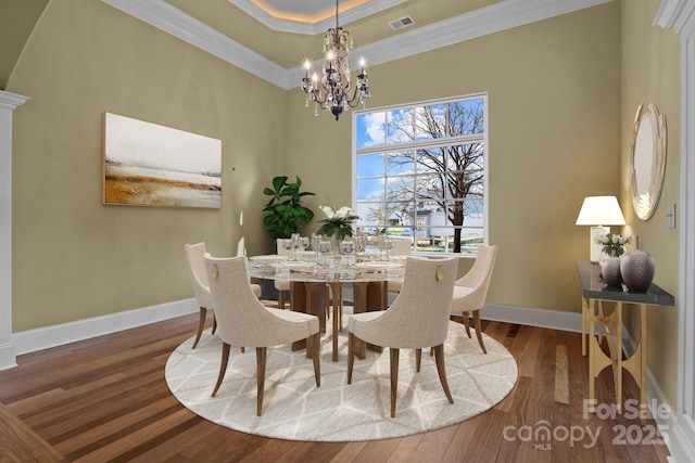 dining room with ornamental molding, a notable chandelier, baseboards, and wood finished floors