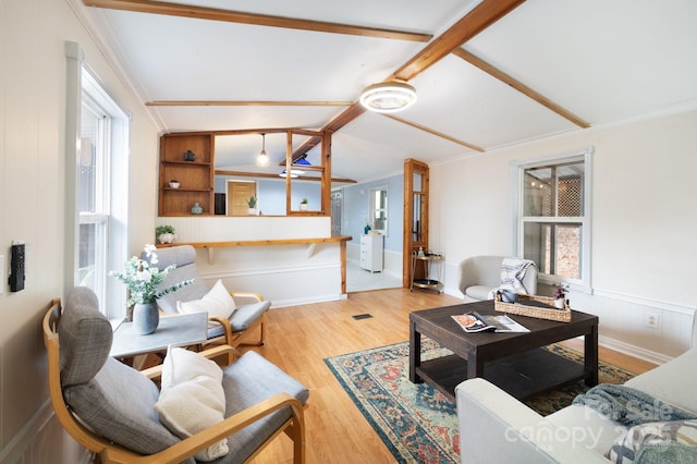 living area with a wainscoted wall, ornamental molding, and wood finished floors