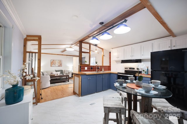 kitchen featuring lofted ceiling with beams, blue cabinets, white cabinetry, freestanding refrigerator, and range hood