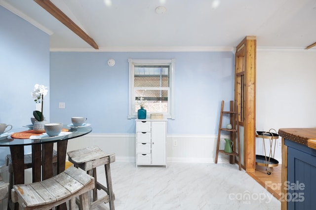 dining space featuring marble finish floor, ornamental molding, wainscoting, and baseboards