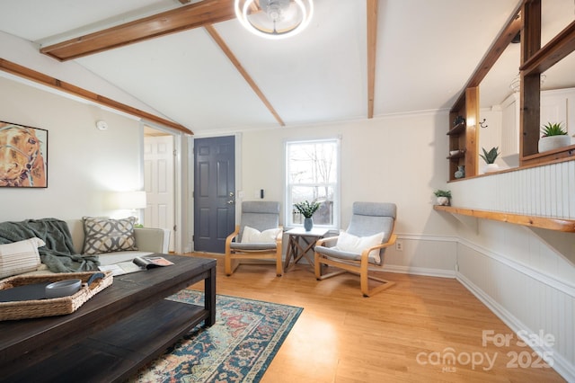 living room with vaulted ceiling with beams, a wainscoted wall, and light wood-style flooring