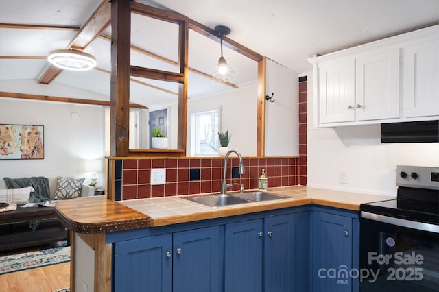 kitchen with blue cabinets, under cabinet range hood, a sink, hanging light fixtures, and stainless steel range with electric stovetop