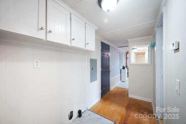 washroom featuring ornamental molding, electric panel, light wood-style flooring, and baseboards