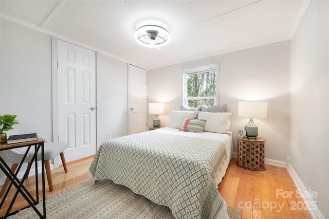 bedroom featuring baseboards, wood finished floors, and ornamental molding